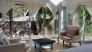 A room with a bed, a chair, a table, and large windows. - Cuch Balam Private Estate with 3 Bedrooms, 2 Hectares of Garden, Pool and Cenote (Chunkanán)