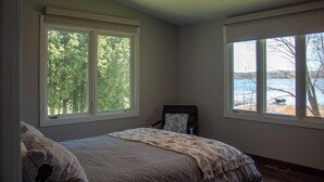 Ein Schlafzimmer mit einem Bett, zwei Fenstern, einem Sessel und einem Deckenventilator.