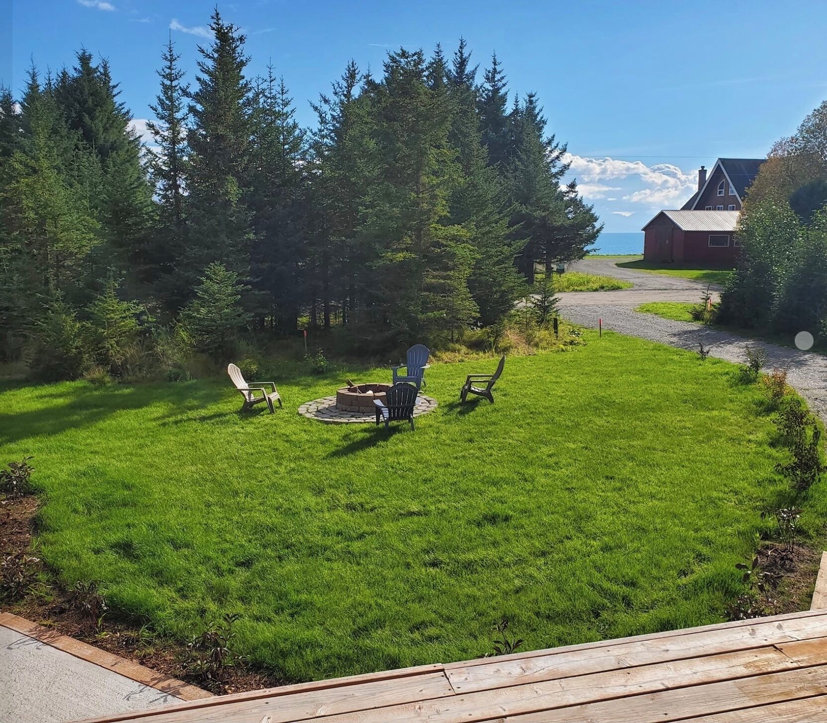 A backyard with a fire pit, chairs, and a wooden deck.