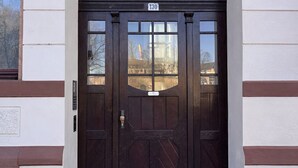 A dark wooden double door with a number plate, set in a building with white and brown siding. - MIILOX Apartments Chemnitz (Chemnitz)