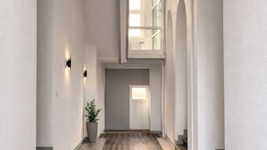 A hallway with patterned flooring, white walls, and a potted plant. - MIILOX Apartments Chemnitz (Chemnitz)