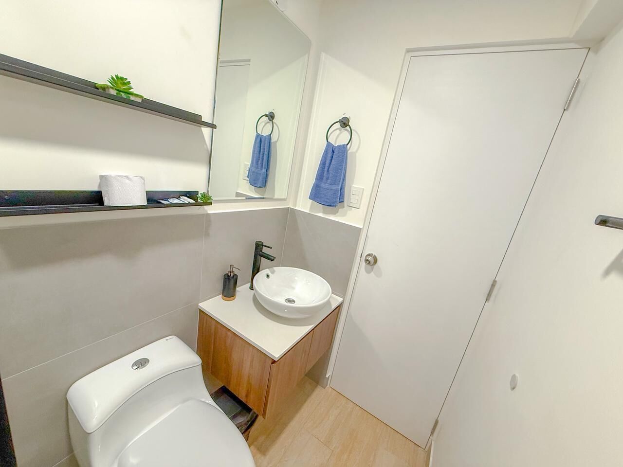 A small bathroom with a toilet, sink, and mirror.