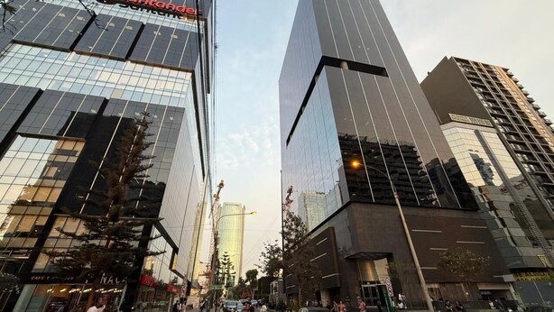 A modern urban street with tall buildings, including a prominent glass-fronted structure with a red logo. - San Isidro financial district stay (404) (Lima)