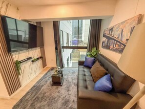 A modern living room with a sofa, a flat-screen TV, a plant, and a painting. - San Isidro financial district stay (404) (Lima)