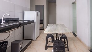 A compact kitchen with a refrigerator, a sink, and a table with stools. - Apartamento Para 6 h Spedes com Wi-fi e Garagem (Para de Minas)