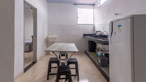 A compact kitchen with a dining table, stools, a refrigerator, and a window. - Apartamento Para 6 h Spedes com Wi-fi e Garagem (Para de Minas)