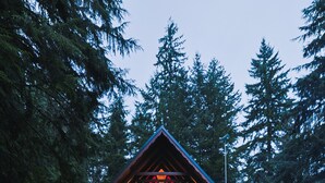 Una cabana amb una foguera, dues cadires Adirondack vermelles i façana de fusta.