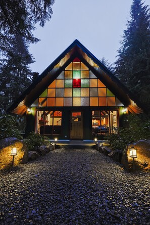 Une maison avec un toit à forte pente, de grandes fenêtres et une allée gravillonnée.