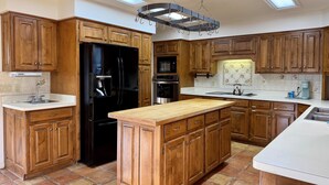 A kitchen with wooden cabinets, a black refrigerator, a central island, and skylights. - Birdie House on Balboa (Hot Springs Village)