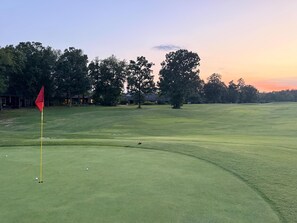 A golf course with a red flag, trees, and a clear sky. - Birdie House on Balboa (Hot Springs Village)