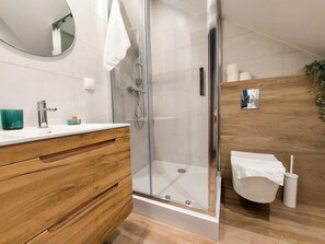 A modern bathroom with a glass shower enclosure, a wooden vanity, and a white sink. - mrhomeapartments-Limba (Kraków)