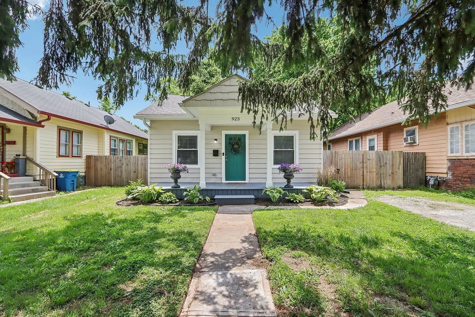 A two-story house with a green door, a front porch, and a pathway leading to the entrance.