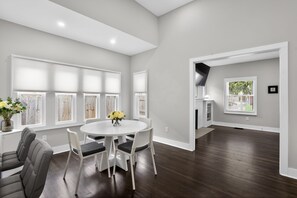 A spacious room with a dining table, chairs, and a vase of flowers. - Near Monon Trail & Fairgrounds | Meridian Kessler (Indianapolis)