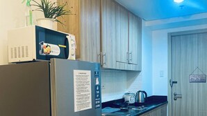 Eine moderne Küche mit Holzausstattung, einem Edelstahlkühlschrank und einer Mikrowelle.