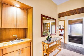 A modern kitchen with wooden cabinets, a sink, and a mirror above a console table with a vase. - Kapalua Ridge | Ocean View 3 BR, Sleeps 12 | Car Incl. w/ 6+ Nights | KRV ML-3663 by KBM (Lahaina)