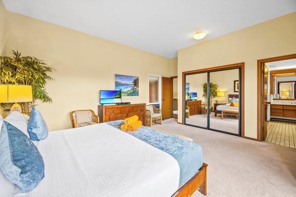 Een hotelkamer met een bed, een bureau, een televisie, een spiegel en een schuifdeur naar een badkamer.