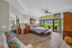 A spacious bedroom with a large bed, a ceiling fan, and a view of a lush garden through a sliding door. - Kapalua Ridge | Ocean View 3 BR, Sleeps 12 | Car Incl. w/ 6+ Nights | KRV ML-3663 by KBM (Lahaina)