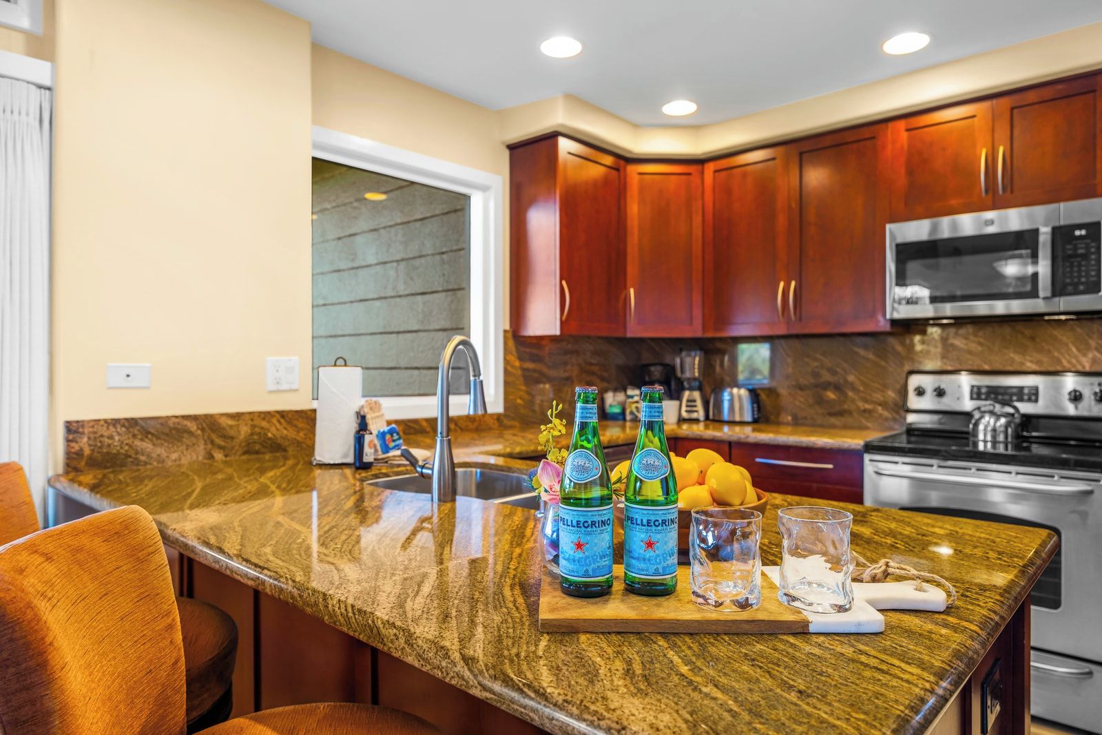 A modern kitchen with a granite countertop, stainless steel appliances, and wooden cabinets.
