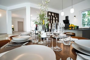 A dining table set with plates, glasses, and cutlery, with a vase of greenery in the center. -  Spacious villa with views of the sea, the Etna volcano, mountains and Taormina. (Sicilia)