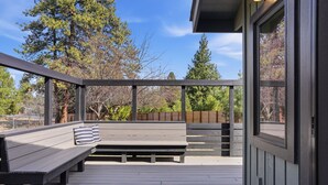 Una terraza de madera con un banco y una ventana.