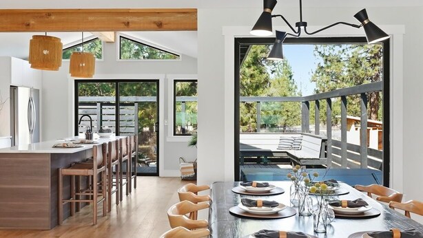 Una cocina moderna con suelo de madera, un comedor con una mesa grande y vistas a una terraza al aire libre.