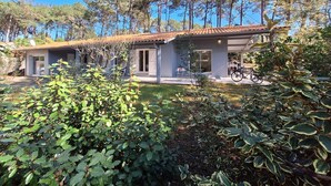 Une maison moderne dotée d’un patio, entourée d’arbres et de verdure.
