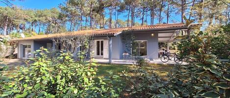 A modern house with a patio, surrounded by trees and greenery.