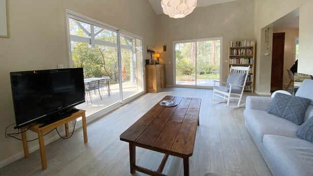 Un salon spacieux avec un grand téléviseur à écran plat, une table basse en bois, un canapé et une bibliothèque.