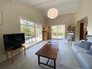 A spacious living room with a large flat-screen TV, a wooden coffee table, a sofa, and a bookshelf. - Villa Marceau - LACANAU (LACANAU)