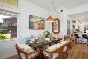 A dining area with a wooden table set for four, surrounded by wicker chairs with cushions. - Kapalua Ridge | Ocean View 6 BR, Sleeps 22 | Car Incl. w/ 6+ Nights | KRV ML-3699 by KBM (Lahaina)