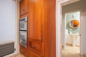 Eine Küche mit Holzausstattung, einem Einbauofen und Blick auf ein Badezimmer mit Waschbecken und Spiegel.