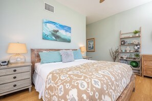 Un dormitorio con cama, mesitas de noche, una repisa y un cuadro.