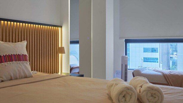 Habitación de hotel con cama, almohadas, una toalla, ventana y vista al exterior.