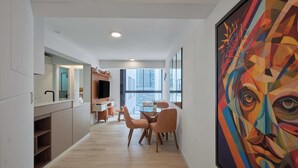 Un interior moderno con comedor, cocina y un cuadro abstracto grande.