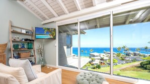 A spacious living room with a large sliding glass door leading to a balcony with a view of the ocean and resort buildings. - Kapalua Bay | Ocean View 3 BR, Sleeps 12 | Car Incl. w/ 6+ Nights | KBV ML-3705 by KBM (Lahaina)