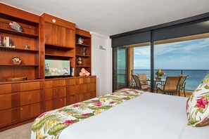 Ein Hotelzimmer mit Balkon, einem Bett mit floralem Bettzeug, Holzmöbeln und Meerblick.
