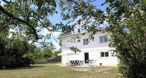 A two-story white house with a patio, outdoor furniture, and a covered seating area.