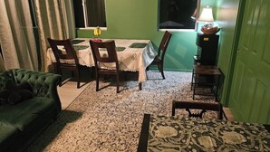 A room with a green wall, a dining table with chairs, a green sofa, a patterned rug, and a lamp. -  3-bedroom Garden house with AC/Hot tub in beautiful Eugene (Eugene)