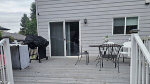 A wooden deck with a railing, a sliding glass door, and a small table with chairs. -  3-bedroom Garden house with AC/Hot tub in beautiful Eugene (Eugene)