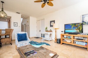 Ein Wohnzimmer mit Sofa, Couchtisch, Fernseher und Deckenventilator.