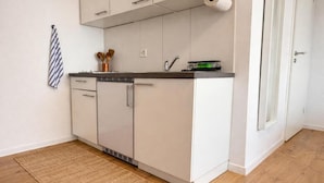 A compact kitchen with white cabinets, a dark countertop, and a small dish rack. - Charming Studio Rheinfall & train station on foot (Neuhausen am Rheinfall)
