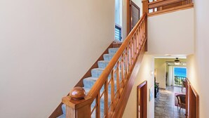 Una escalera de madera con barandilla que lleva a una habitación con vista al océano.