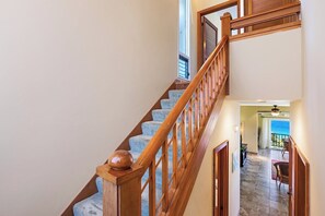 Eine Holztreppe mit Handlauf, die zu einem Zimmer mit Meerblick führt.