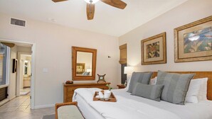 Un dormitorio con una cama grande, un aparador de madera, un espejo y dos cuadros en la pared.
