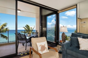 A balcony with a view of the ocean, a sofa, a chair, and a table with chairs. - Mahana Villas | Oceanfront 4 BR Sleeps 12 | Car Incl. w/ 6+ Nights | MAH ML-3747 by KBM (Lahaina)
