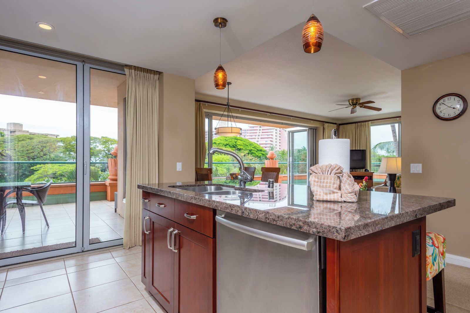 A modern kitchen with a large island, a built-in dishwasher, and a view of the outdoors.