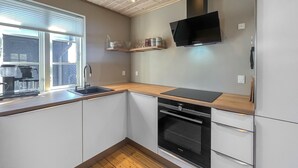 Uma cozinha com forno embutido, cafeteira e janela com persianas.