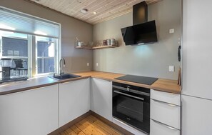 A kitchen with a built-in oven, a coffee maker, and a window with blinds. - 2 bedroom amazing home in Slagelse (Slagelse)