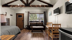 Een knus ingerichte kamer met een bed, een houten tafel, een bank, een televisie en een open haard.