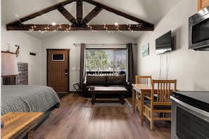 Ein gemütliches Zimmer mit einem Bett, einem Holztisch, einer Couch, einem Fernseher und einem Kamin.